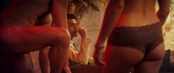 Movie still from “The Devil's Double” (2011), directed by Lee Tamahori – A man sitting in front of a group of women; Medium shot, Over the shoulder angle