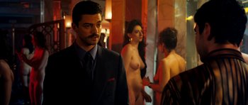 Movie still from “The Devil's Double” (2011), directed by Lee Tamahori – A man in a suit standing in front of two women; Medium shot, Over the shoulder angle