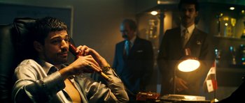 Movie still from “The Devil's Double” (2011), directed by Lee Tamahori – A man smoking a cigarette in front of another man; Medium shot, Low angle