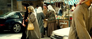 Movie still from “The Devil's Double” (2011), directed by Lee Tamahori – A group of people standing in a market area; Wide shot, Over the shoulder angle