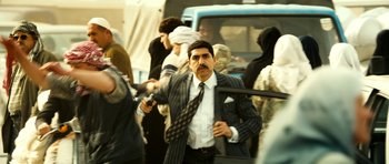 Movie still from “The Devil's Double” (2011), directed by Lee Tamahori – A man in a suit and tie holding a cell phone; Medium shot, Over the shoulder angle