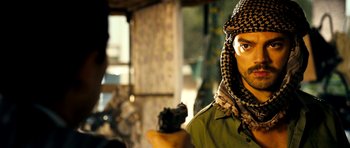 Movie still from “The Devil's Double” (2011), directed by Lee Tamahori – A man holding a gun while wearing a keffiyeh; Close Up shot, Over the shoulder angle