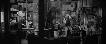 Movie still from “The Diary of Anne Frank” (1959), directed by George Stevens – A man standing in front of a room filled with pots and pans; Wide shot, High angle