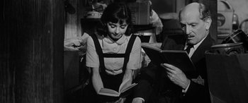 Movie still from “The Diary of Anne Frank” (1959), directed by George Stevens – A woman sitting on the floor reading a book; Medium shot, Over the shoulder angle