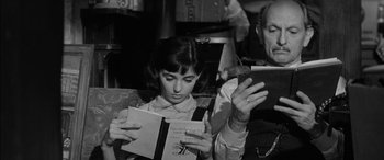 Movie still from “The Diary of Anne Frank” (1959), directed by George Stevens – A girl is reading a book while sitting in a chair; Close Up shot, High angle
