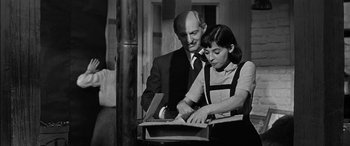 Movie still from “The Diary of Anne Frank” (1959), directed by George Stevens – A man and a woman looking at something in a box; Medium shot, High angle