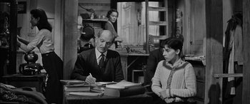 Movie still from “The Diary of Anne Frank” (1959), directed by George Stevens – An older man and woman sitting at a table; Medium shot, High angle