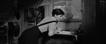 Movie still from “The Diary of Anne Frank” (1959), directed by George Stevens – A woman leaning over a table with a cup of coffee; Medium shot, High angle