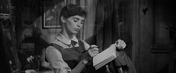 Movie still from “The Diary of Anne Frank” (1959), directed by George Stevens – A woman writing in a notebook while sitting in a chair; Close Up shot, High angle