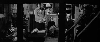 Movie still from “The Diary of Anne Frank” (1959), directed by George Stevens – An old black and white photo of a man and woman and an older man; Medium shot, Low angle