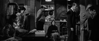 Movie still from “The Diary of Anne Frank” (1959), directed by George Stevens – A man and a woman sitting in a kitchen next to each other; Wide shot, High angle