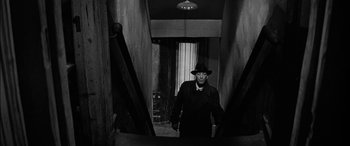 Movie still from “The Diary of Anne Frank” (1959), directed by George Stevens – A black and white photo of a man in a suit and hat; Medium shot, Low angle