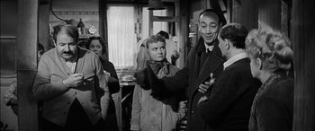 Movie still from “The Diary of Anne Frank” (1959), directed by George Stevens – An old black and white photo of a group of people; Medium shot, Over the shoulder angle
