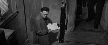 Movie still from “The Diary of Anne Frank” (1959), directed by George Stevens – An old photo of a man looking at a clipboard; Medium shot, Low angle