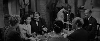 Movie still from “The Diary of Anne Frank” (1959), directed by George Stevens – A black and white photo of people sitting at a dinner table; Medium shot, Over the shoulder angle