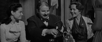 Movie still from “The Diary of Anne Frank” (1959), directed by George Stevens – An older man in a suit and bow tie holding a spoon; Medium shot, Over the shoulder angle