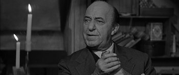 Movie still from “The Diary of Anne Frank” (1959), directed by George Stevens – An older man wearing a suit and tie clasping his hands; Close Up shot, Over the shoulder angle