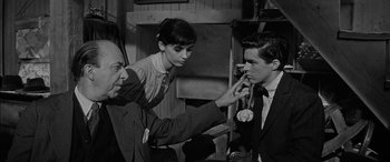 Movie still from “The Diary of Anne Frank” (1959), directed by George Stevens – An old photo of a man and a woman looking at another man; Medium shot, Over the shoulder angle