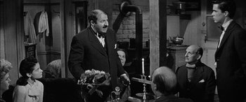 Movie still from “The Diary of Anne Frank” (1959), directed by George Stevens – An older man standing in front of two other men; Medium shot, Over the shoulder angle