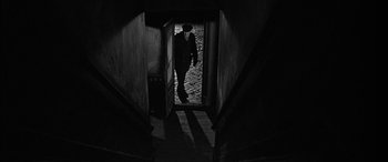 Movie still from “The Diary of Anne Frank” (1959), directed by George Stevens – A man in a suit and tie walking down a dark hallway; Wide shot, High angle