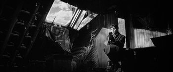 Movie still from “The Diary of Anne Frank” (1959), directed by George Stevens – A man sitting on a chair holding a cell phone; Medium shot, Low angle
