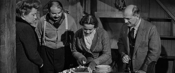 Movie still from “The Diary of Anne Frank” (1959), directed by George Stevens – An old photo of a woman cutting a cake; Medium shot, High angle