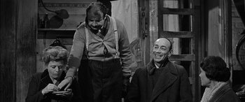 Movie still from “The Diary of Anne Frank” (1959), directed by George Stevens – A man standing next to another man in a room; Medium shot, Over the shoulder angle