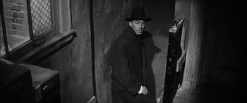 Movie still from “The Diary of Anne Frank” (1959), directed by George Stevens – A man wearing a hat and a black coat; Medium shot, Low angle