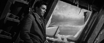 Movie still from “The Diary of Anne Frank” (1959), directed by George Stevens – A black and white photo of a man standing in front of an airplane window; Medium shot, Low angle