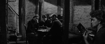 Movie still from “The Diary of Anne Frank” (1959), directed by George Stevens – A group of people playing a game of chess; Medium shot, High angle