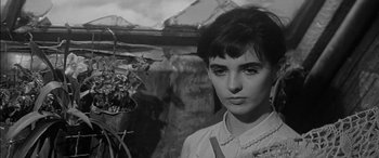 Movie still from “The Diary of Anne Frank” (1959), directed by George Stevens – Black and white photograph of a young woman in front of a plant; Close Up shot, High angle