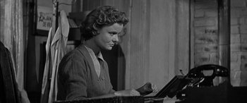 Movie still from “The Diary of Anne Frank” (1959), directed by George Stevens – An old black and white photo of a woman using a computer; Close Up shot, Low angle