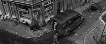 Movie still from “The Diary of Anne Frank” (1959), directed by George Stevens – An aerial view of two men unloading luggage from a truck; Extreme Wide shot, High angle