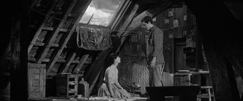 Movie still from “The Diary of Anne Frank” (1959), directed by George Stevens – A man and a woman are standing in an attic; Wide shot, High angle