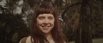 Movie still from “The Diary of a Teenage Girl” (2015), directed by Marielle Heller – A person smiling with trees in the background; Close Up shot, Low angle