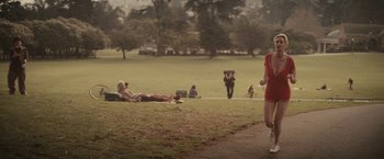 Movie still from “The Diary of a Teenage Girl” (2015), directed by Marielle Heller – A group of people sitting in a field with an animal in the background; Wide shot, High angle