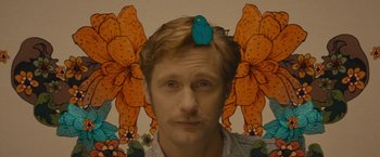 A man with a blue bird on his head