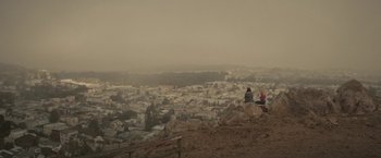 Movie still from “The Diary of a Teenage Girl” (2015), directed by Marielle Heller – Two people sitting on top of a hill overlooking a city; Extreme Wide shot, High angle
