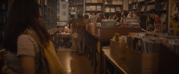 Movie still from “The Diary of a Teenage Girl” (2015), directed by Marielle Heller – A group of people standing in a room with books; Wide shot, Over the shoulder angle