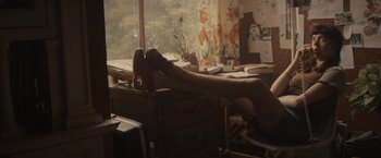 Movie still from “The Diary of a Teenage Girl” (2015), directed by Marielle Heller – A woman with her legs on top of a desk; Wide shot, High angle