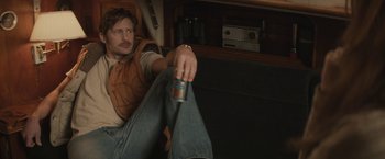 Movie still from “The Diary of a Teenage Girl” (2015), directed by Marielle Heller – A man sitting on the floor holding a can of beer; Medium shot, Over the shoulder angle