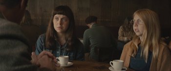Movie still from “The Diary of a Teenage Girl” (2015), directed by Marielle Heller – A woman sitting at a table with a cup of coffee; Close Up shot, Over the shoulder angle