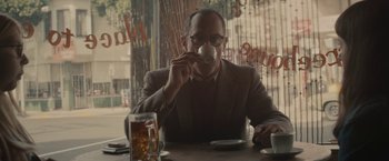 Movie still from “The Diary of a Teenage Girl” (2015), directed by Marielle Heller – A man sitting at a table drinking a cup of coffee; Medium shot, Over the shoulder angle