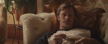 Movie still from “The Diary of a Teenage Girl” (2015), directed by Marielle Heller – A man sitting on a couch eating food; Close Up shot, High angle