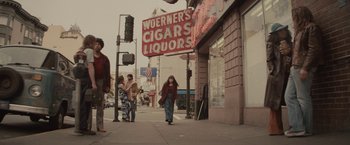 Movie still from “The Diary of a Teenage Girl” (2015), directed by Marielle Heller – A woman walking down the street in front of a liquor store; Extreme Wide shot, Low angle