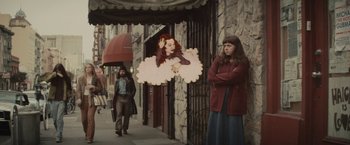 Movie still from “The Diary of a Teenage Girl” (2015), directed by Marielle Heller – A woman standing in front of a building with an image of a woman; Wide shot, Over the shoulder angle