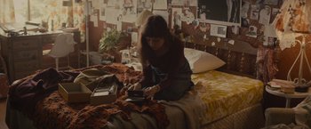 Movie still from “The Diary of a Teenage Girl” (2015), directed by Marielle Heller – A woman sitting on top of a bed holding a phone; Medium shot, High angle