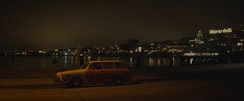 Movie still from “The Diary of a Teenage Girl” (2015), directed by Marielle Heller – An old car parked on the side of the road by the water at night; Extreme Wide shot, Low angle
