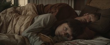 Movie still from “The Diary of a Teenage Girl” (2015), directed by Marielle Heller – A woman laying on a bed with a cell phone in her hand; Close Up shot, Overhead angle