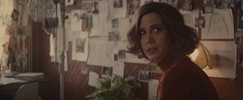 Movie still from “The Diary of a Teenage Girl” (2015), directed by Marielle Heller – A person holding a plant in a room; Close Up shot, Over the shoulder angle